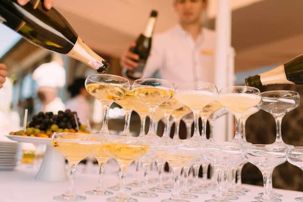 champagne being poured into tower of glasses